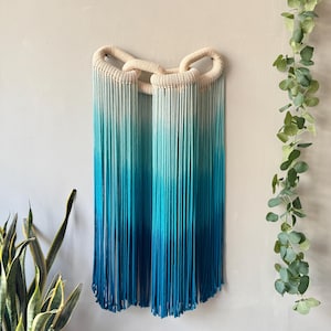 以下が含まれることがあります： 黒い持ち手と「But First, Coffee」のテキストが黒い太字で書かれた白いセラミックマグ。マグカップはぼやけた背景に置かれており、居心地の良い環境を示唆しています。