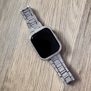 Puede incluir: Un reloj inteligente de tono plateado con una pantalla negra rectangular y una correa de eslabones met&aacute;licos a juego. Tanto la caja del reloj como toda la longitud de la correa est&aacute;n incrustadas con peque&ntilde;as piedras claras y brillantes.