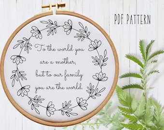 May include: A black and white embroidery hoop with a floral wreath design and the text "To the world you are a mother, but to our family you are the world."  PDF PATTERN is written in the top right corner.