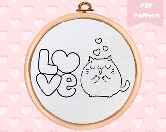 Może przedstawiać: Wzór do haftu w kolorze czarnym i białym przedstawiający kota z sercami nad głową i słowem "LOVE" w sercowatym kroju czcionki.