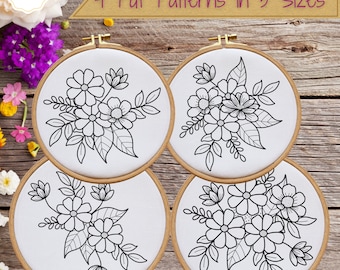 May include: Four embroidery hoops with floral designs. Each hoop features a white fabric with a black outline of flowers and leaves. The hoops are made of wood and are arranged on a wooden surface. Text reads "4 Pdf Patterns in 5 Sizes."