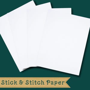 Può includere: Una pila di fogli bianchi di Stick & Stitch Paper su sfondo verde scuro. La carta è rettangolare e sembra vuota. Il testo "Stick & Stitch Paper" è visualizzato in un banner marrone nella parte inferiore dell'immagine.