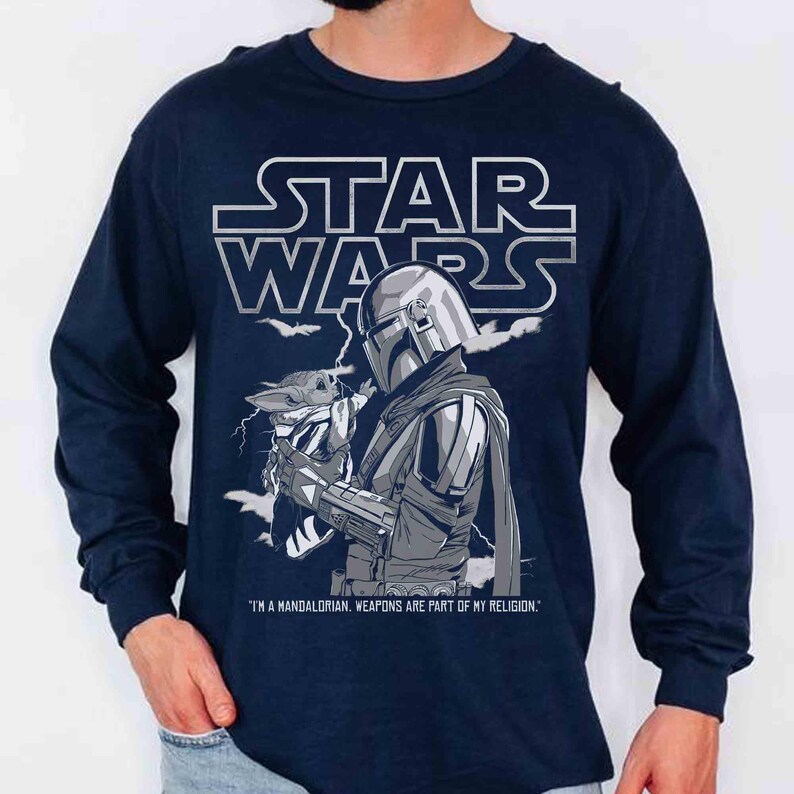 Op de afbeelding: Marineblauwe longsleeve met een Star Wars-ontwerp. Het toont The Mandalorian met Grogu, met de tekst "I'M A MANDALORIAN, WEAPONS ARE PART OF MY RELIGION."