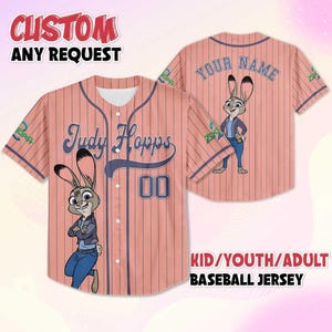 May include: A baseball jersey with a pink and navy blue pinstripe design. The front features the name "Judy Hopps" and the number "00", along with a cartoon character. The back has the text "YOUR NAME" and a cartoon character. The text "CUSTOM ANY REQUEST" and "KID/YOUTH/ADULT BASEBALL JERSEY" are also visible.