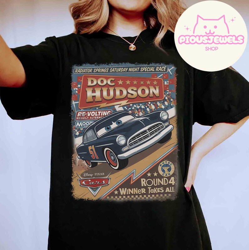 May include: Black t-shirt featuring a vintage-style graphic of Doc Hudson from the Disney Pixar Cars movie. The design includes the text "RADIATOR SPRINGS SATURDAY NIGHT SPECIAL RACE" and "ROUND 4 WINNER TAKES ALL".