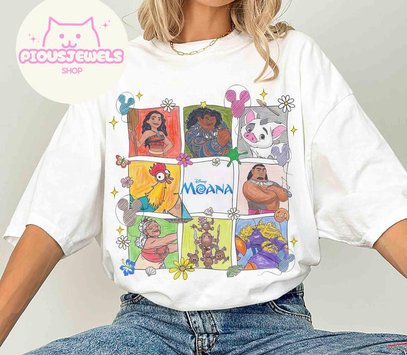 Pu&ograve; includere: T-shirt bianca con una grafica colorata dei personaggi del film Disney Moana. Il design include illustrazioni di Moana, Maui, Hei Hei, Pua e altri, disposti in un motivo a griglia. &Egrave; presente anche la parola "Moana".
