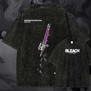 Könnte beinhalten: Ein schwarzes T-Shirt in Acid-Wash-Optik mit einer Grafik eines Schwerts mit violetten Akzenten und dem Text SENBONZAKURA Bankai auf der Rückseite. Die Vorderseite zeigt das Wort BLEACH in weißem Text mit violetten japanischen Schriftzeichen.
