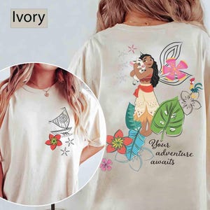 May include: Ivory-coloured t-shirt with a sailboat and floral design on the front. The back features a cartoon illustration of a character holding a pig, and the text "Your adventure awaits".