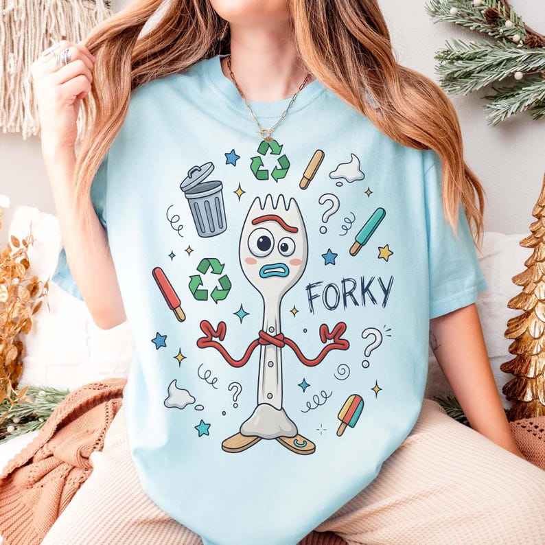 May include: Light blue t-shirt featuring a cartoon illustration of Forky from Toy Story. The design includes a fork character with a worried expression, surrounded by recycling symbols, stars, and the word "Forky".