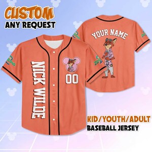Puede incluir: Camiseta de b&eacute;isbol naranja con ribete negro, con el texto "NICK WILDE" verticalmente en la parte delantera y un personaje de zorro de dibujos animados. La camiseta incluye el texto "YOUR NAME" y la marca "Zootopia". Disponible en tallas para ni&ntilde;os, j&oacute;venes y adultos.