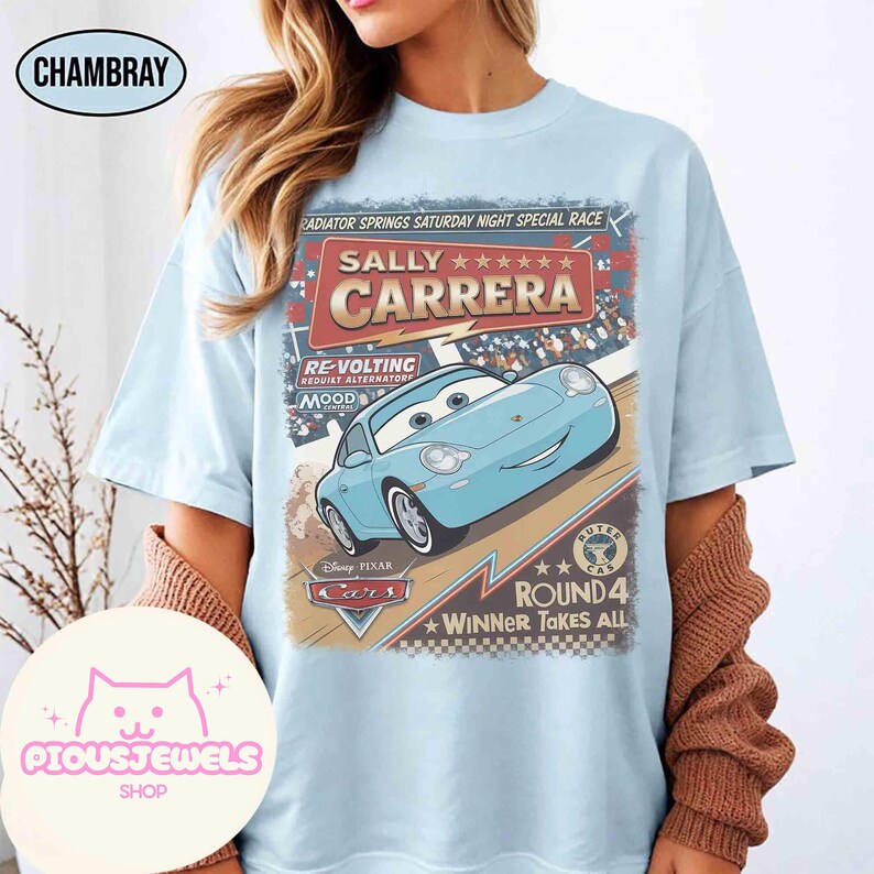 May include: Light blue t-shirt featuring a graphic of Sally Carrera from the Disney Pixar Cars movie. The design includes text that reads "Radiator Springs Saturday Night Special Race" and "Winner Takes All."