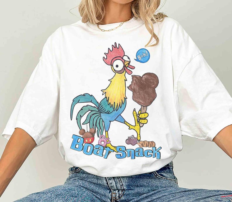 May include: White t-shirt with a colorful cartoon rooster holding a chocolate ice cream bar. The rooster has a red comb, yellow neck, and blue tail feathers. The text "Boat Snack" is printed in blue.