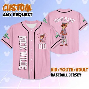 Puede incluir: Camiseta de b&eacute;isbol rosa con ribete negro, con el personaje Nick Wilde de Zootopia. La parte delantera muestra "NICK WILDE" verticalmente y el n&uacute;mero "00". La parte trasera tiene "YOUR NAME" y un gr&aacute;fico de personaje.