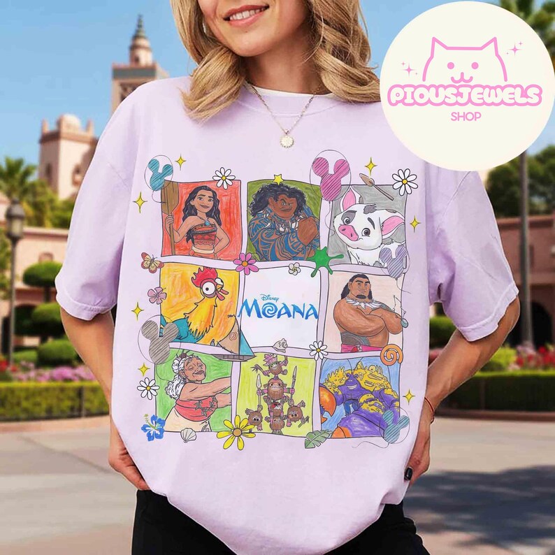 Pu&ograve; includere: Una maglietta lilla chiaro con una grafica colorata dei personaggi del film Disney Moana. Il design include Moana, Maui, Pua, Hei Hei e altri personaggi. Il testo "Moana" &egrave; anch'esso presente.
