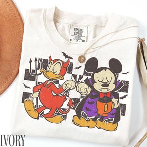 ミッキーマウスとドナルドダックのハロウィンシャツ、ディズニーベストフレンズコンフォートカラーズTシャツ、チェック柄の吸血鬼と悪魔の幼児用ディズニーランド旅行シャツ