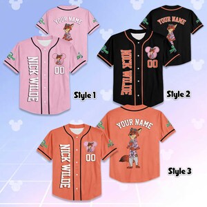 Puede incluir: Tres camisetas de b&eacute;isbol en rosa, negro y naranja, cada una con un personaje de zorro de dibujos animados. Las camisetas tienen el texto "NICK WILDE" y "YOUR NAME", junto con el n&uacute;mero "00". Las camisetas son de manga corta.