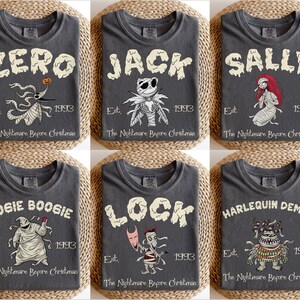 K&ouml;nnte beinhalten: Sechs anthrazitfarbene T-Shirts mit Charakteren aus "The Nightmare Before Christmas". Jedes Shirt zeigt den Namen eines Charakters in einer verwaschenen Schriftart, eine Illustration und den Text "Est. 1993 The Nightmare Before Christmas."