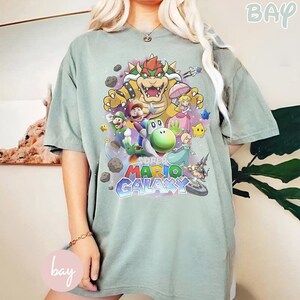 K&ouml;nnte beinhalten: Eine wei&szlig;e Keramik-Tasse mit schwarzem Henkel und dem Text "But First, Coffee" in schwarzer, fetter Schrift. Die Tasse steht auf einer Holzoberfl&auml;che.