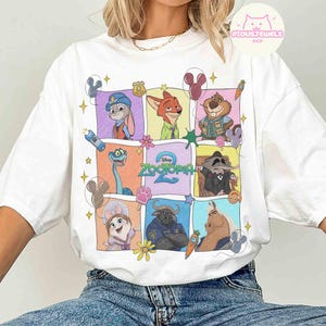 May include: White t-shirt featuring a colorful grid of Zootopia 2 characters. The design includes Judy Hopps, Nick Wilde, and other characters in a cartoon style. The shirt has a crew neck and short sleeves.