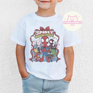 Puede incluir: Camiseta blanca con un gr&aacute;fico colorido de Spidey y sus Incre&iacute;bles Amigos. El dise&ntilde;o incluye a Spider-Man, Iron Man, Hulk y otros personajes. La camiseta tiene el texto "Spidey Amazing Friends".