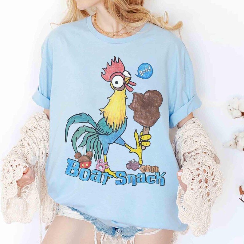 May include: Light blue t-shirt featuring a cartoon rooster holding a chocolate ice cream bar. The rooster is yellow, blue, and red, with the text "Boat Snack" in blue. A speech bubble says "Bok!".