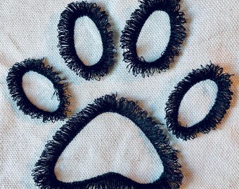 May include: Black paw print embroidered on a white fabric background.