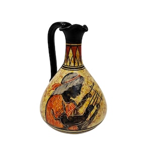 Può includere: Brocca in ceramica dipinta a mano con manico e bordo neri. La brocca presenta una dettagliata illustrazione di una persona che suona uno strumento a corde, con accenti arancioni e neri su sfondo color crema. La brocca è un oggetto decorativo.