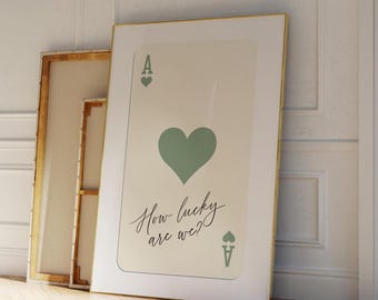 Op de afbeelding: Een ingelijste print van een aas harten speelkaart met een groen hart en de tekst "How lucky are we?"