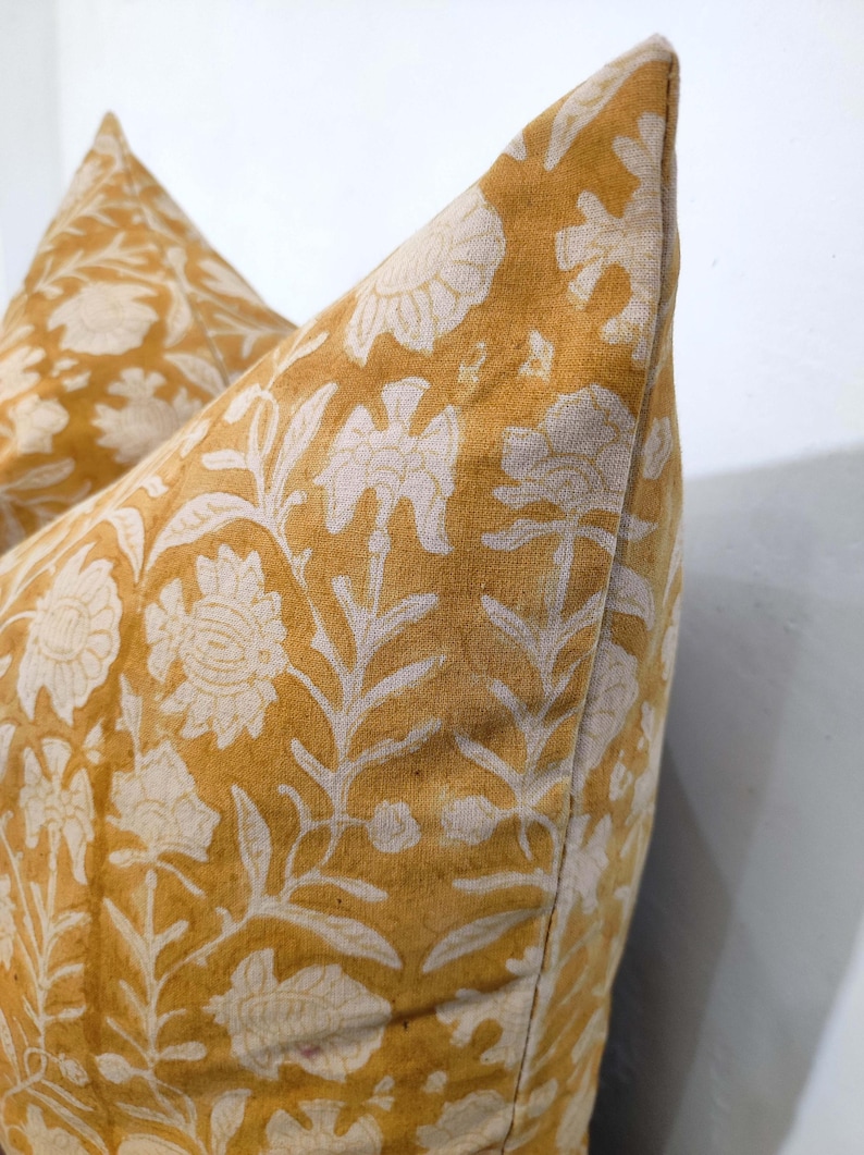 May include: Two mustard yellow pillowcases with a white floral pattern. The pillowcases are made of a soft, textured fabric.