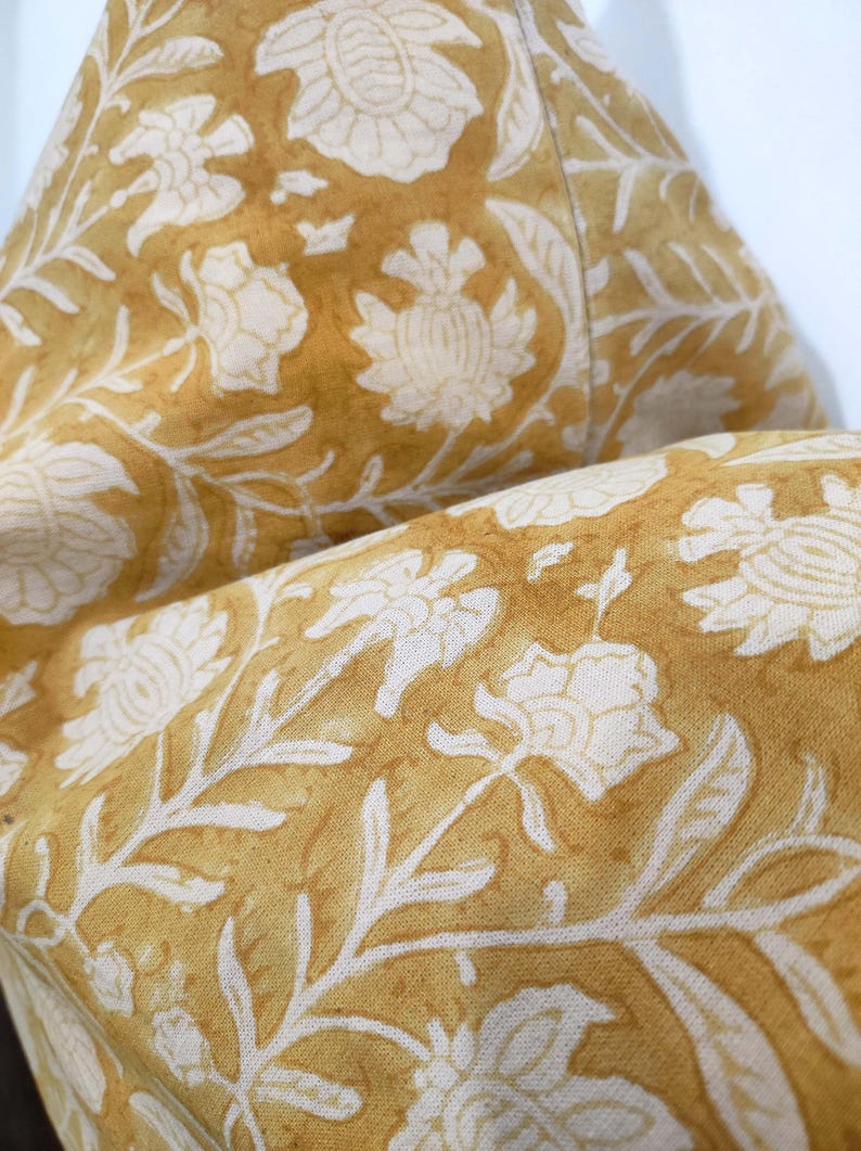 May include: A close-up of a yellow fabric with a white floral pattern. The fabric is soft and has a subtle sheen.