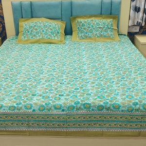 Könnte beinhalten: Ein grünes und weißes Blumenbettwäsche-Set mit grünem Rand. Das Bettlaken liegt auf einem Bett mit zwei grünen und weißen Blumenkissenbezügen.