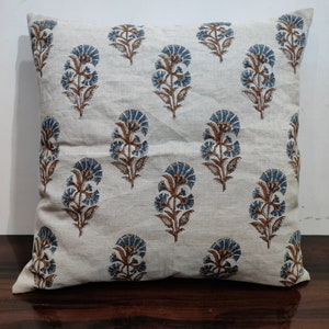 Könnte beinhalten: Ein weißer Kissenbezug mit einem blauen und braunen Blumenmuster. Der Kissenbezug ist aus einem weichen, natürlichen Stoff.