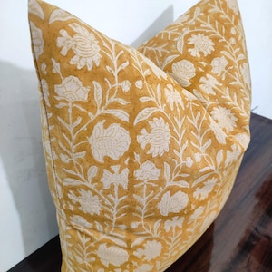 May include: A yellow cushion with a white floral pattern. The cushion is made of cotton and has a square shape.