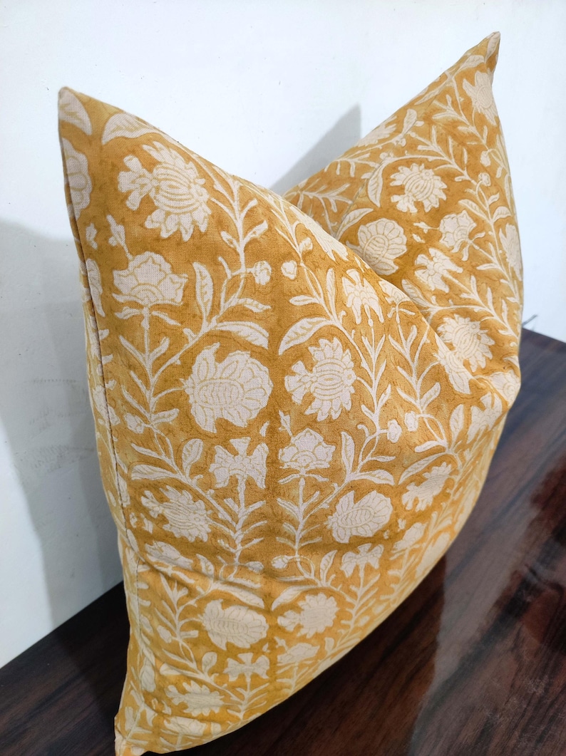 May include: A yellow cushion with a white floral pattern. The cushion is made of cotton and has a square shape.