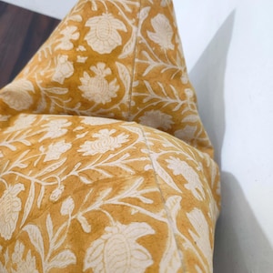 May include: A yellow cushion with a white floral pattern. The cushion is made of a soft, comfortable fabric and has a subtle sheen.