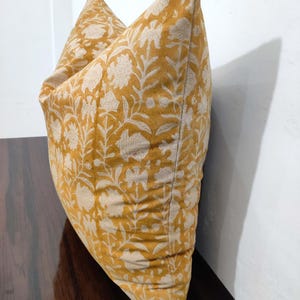 May include: A yellow cushion with a white floral pattern. The cushion is made of a soft, comfortable fabric and has a subtle sheen.