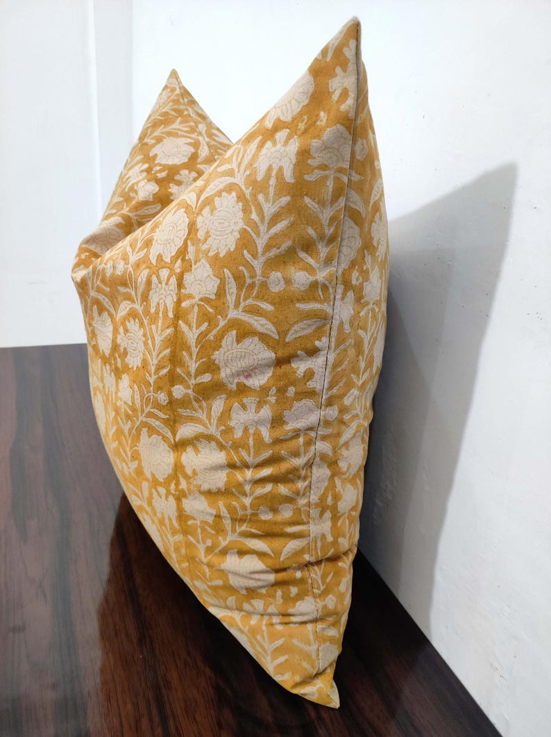 May include: A yellow cushion with a white floral pattern. The cushion is made of a soft, comfortable fabric and has a subtle sheen.