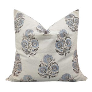 Puede incluir: Una funda de almohada blanca con un patrón floral azul y marrón. La funda de almohada presenta un diseño repetitivo de flores estilizadas con detalles intrincados.