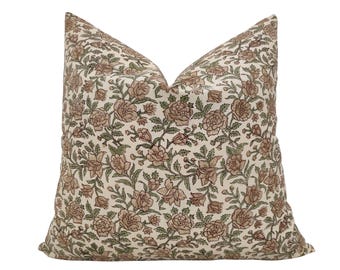 May include: A square cushion with a floral design. The cream-coloured fabric is covered in a repeating pattern of brown and green flowers and leaves. The cushion is designed for decorative use and would suit a living room or bedroom.