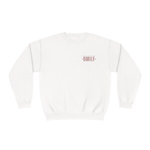 May include: White sweatshirt with a pink graphic that says -DMILF- on the front.