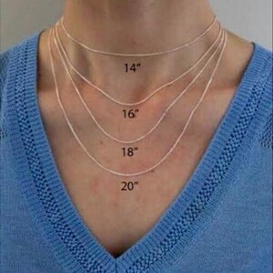 Pode incluir: Quatro colares de prata de diferentes comprimentos, exibidos no peito de uma pessoa. Os colares s&atilde;o rotulados com seus comprimentos: 35,5 cm, 40,6 cm, 45,7 cm e 50,8 cm. A pessoa est&aacute; vestindo um su&eacute;ter azul.