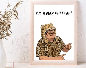 May include: A framed art print featuring a cartoon illustration of a person wearing a leopard print hat and matching shirt, with black-rimmed glasses and a goatee. The text I'M A MAN CHEETAH! is printed in black above the figure on a white background.