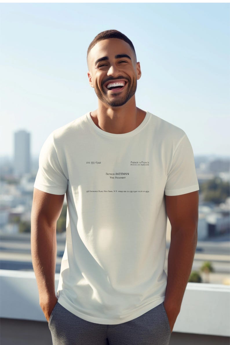 May include: A cream-colored short-sleeve t-shirt featuring black printed text that mimics a business card. The text reads Pierce & Pierce, Patrick Bateman, Vice President, and includes a New York address and phone number 212 555 6342.