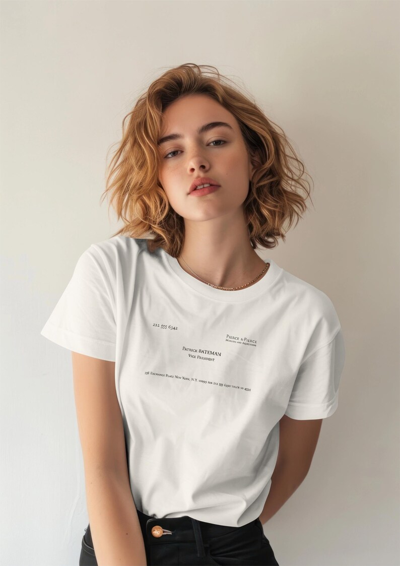 May include: A white short-sleeved t-shirt featuring black printed text that mimics a business card. The text includes the name Patrick Bateman, the title Vice President, the company Pierce & Pierce, and an address in New York, New York.