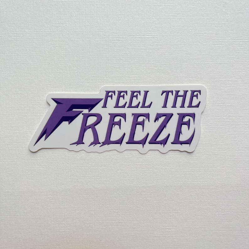 May include: A white sticker with the text "FEEL THE FREEZE" in purple. The sticker has a purple and white design with a jagged edge.