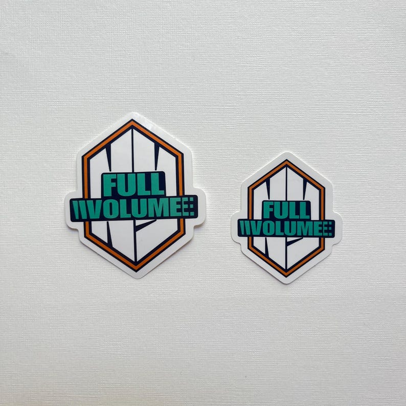 May include: Two white hexagon stickers with the text "FULL VOLUME!!" in teal and white. The stickers have a black and orange border. One sticker is larger than the other.