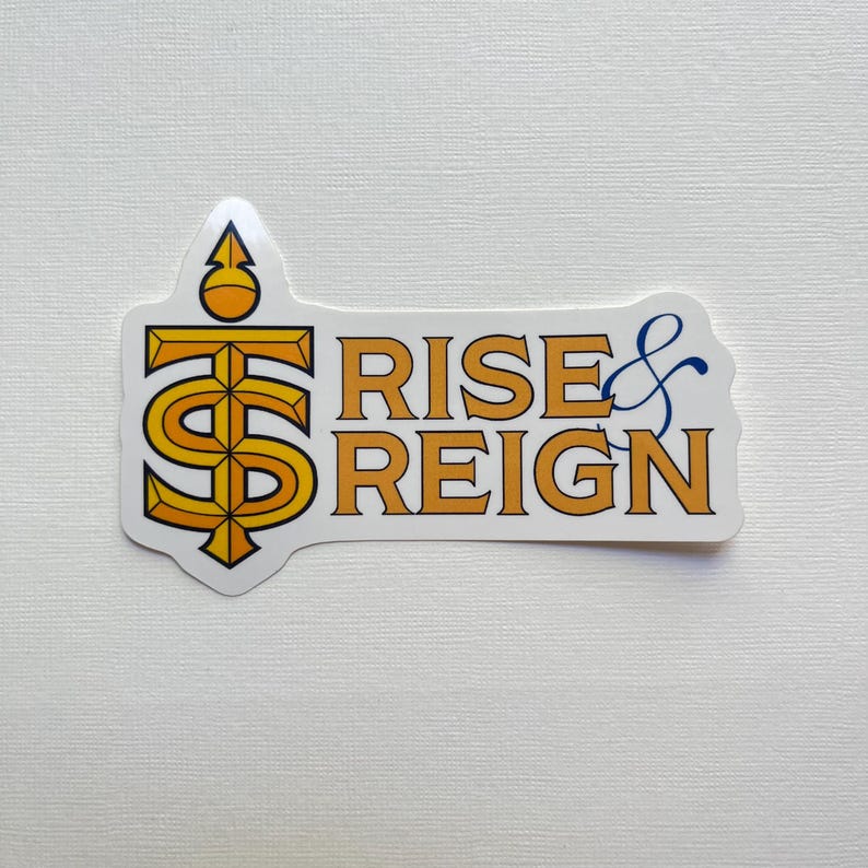 May include: A white sticker with the words "RISE & REIGN" in orange and blue. The sticker has an orange and yellow graphic of a stylized dollar sign. The sticker is on a white background.