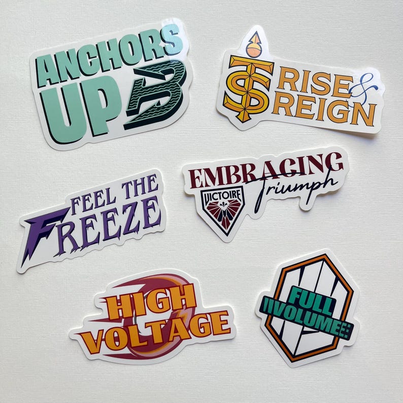 May include: A collection of colorful stickers with various phrases. The stickers include "ANCHORS UP", "RISE & REIGN", "FEEL THE FREEZE", "EMBRACING triumph", "HIGH VOLTAGE", and "FULL VOLUME!". The stickers have a white border and are on a white surface.