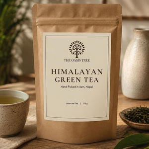 Könnte beinhalten: Ein brauner Papiersack mit Himalaya-Grüntee und einem weißen Etikett mit einem Baumlogo und Text. Auf dem Etikett steht "THE OASIS TREE, HIMALAYAN GREEN TEA, Hand-Picked in Ilam, Nepal, Loose Leaf Tea, 100 g". Eine Tasse Tee und Teeblätter sind sichtbar.