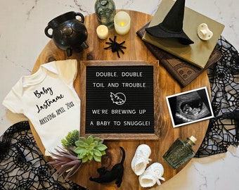 May include: A Halloween-themed baby announcement with a white onesie that says "Baby Lastname Arriving April 20XX", a letter board that says "Double, Double Toil and Trouble... We're Brewing Up A Baby To Snuggle!" and a black and white ultrasound image.